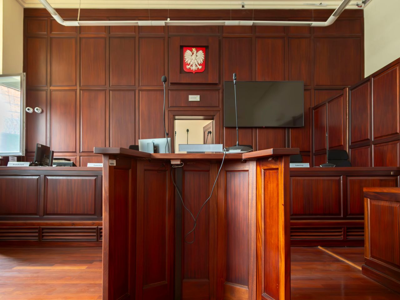 Strona główna A detailed view of a courtroom interior in Wrocław, Poland, showcasing the judge's bench and national emblem.